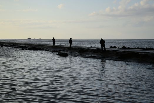 Photo of fishers silhouettes at pier. Taken in Riga.