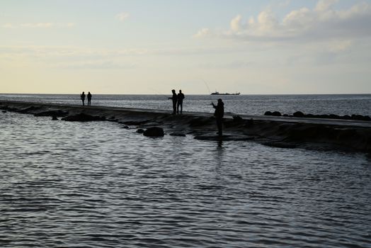 Photo of fishers silhouettes at pier. Taken in Riga.