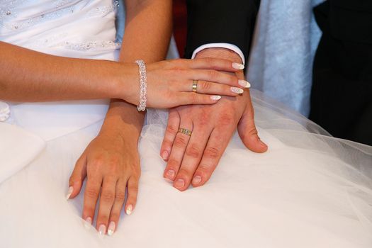 Bride keeping grooms hand during wedding ceremony in the church 