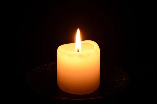 Photo of a burning candle on a black background. Object photography.