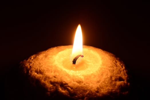 Photo of a burning candle on a black background. Object photography.