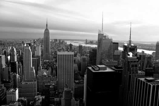 Horizontal aerial view of the Manhattan section of New York City including all of the buildings and skyline in black and white.