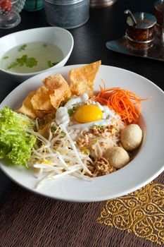 Gai pad bai gaprow style Thai dish with fried egg and rice noodles.