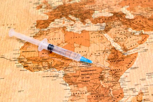 Photo of syringe on a map of africa, antique style. May be used as illustration for medical theme.