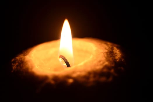 Photo of a burning candle on a black background. Objects photography.