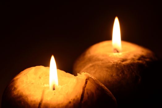 Photo of two burning candles on a black background. Objects photography.