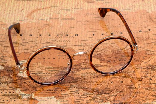 Photo of glasses on a map of a world, antique style. Focus on Russia. May be used as illustration for traveling theme.