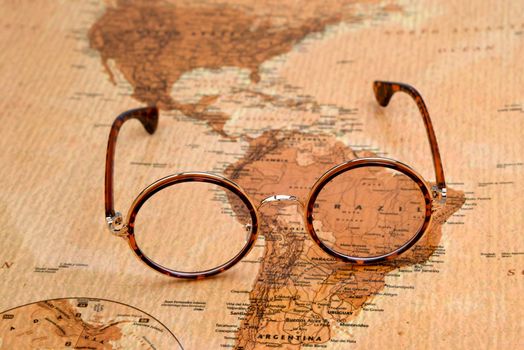 Photo of glasses on a map of a world, antique style. Focus on Brazil. May be used as illustration for traveling theme.