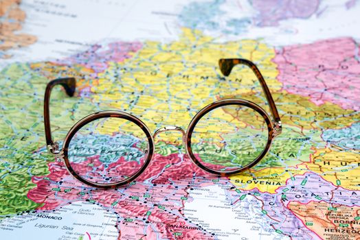 Photo of glasses on a map of europe. Focus on Switzerland. May be used as illustration for traveling theme.