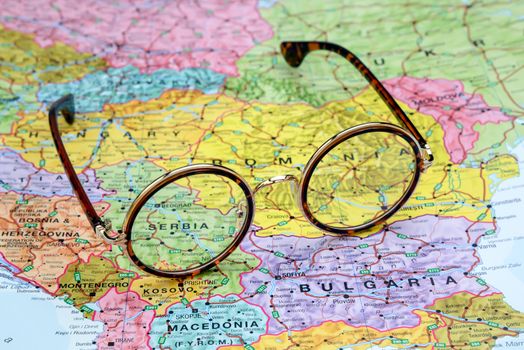 Photo of glasses on a map of europe. Focus on Serbia. May be used as illustration for traveling theme.