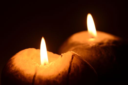 Photo of two burning candles on a black background. Objects photography.