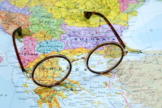 Photo of glasses on a map of europe. Focus on Greece. May be used as illustration for traveling theme.