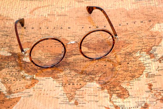 Photo of glasses on a map of a world, antique style. Focus on Russia. May be used as illustration for traveling theme.