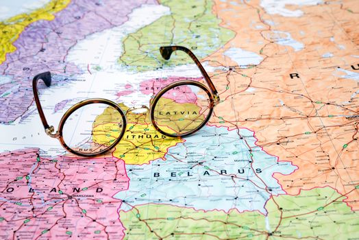 Photo of glasses on a map of europe. Focus on Latvia. May be used as illustration for traveling theme.