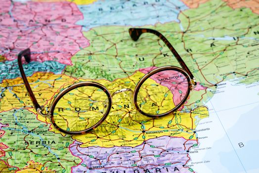 Photo of glasses on a map of europe. Focus on Romania. May be used as illustration for traveling theme.