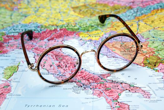 Photo of glasses on a map of europe. Focus on Italy. May be used as illustration for traveling theme.