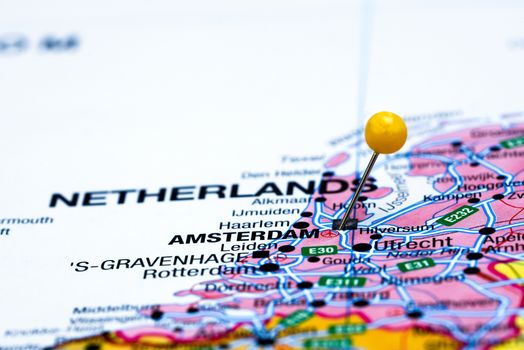 Photo of pinned Amsterdam on a map of europe. May be used as illustration for traveling theme.