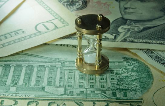 Miniature hourglass on top of dollar banknotes