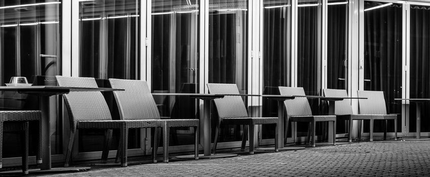 Empty chairs and tables at a cafe terrace at night