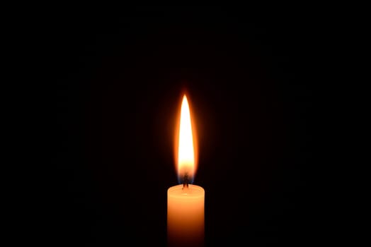 Photo of a white candle burning on a black background.