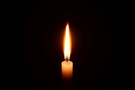 Photo of a white candle burning on a black background.