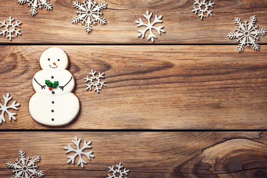 Christmas background with gingerbread cookie in shape of snowman on wooden table. Copy space. Top view