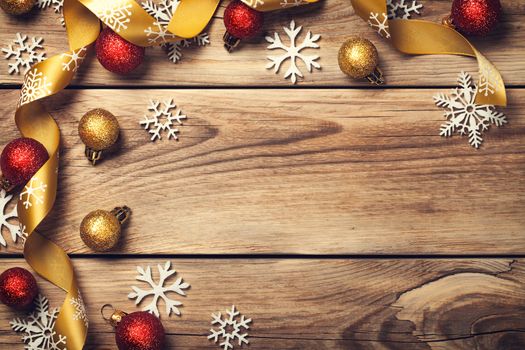 Christmas background with snowflakes, red and gold balls on wooden table. Copy space. Top view