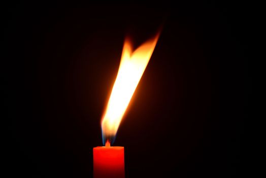 Photo of a red candle burning on a black background. Objects photography.