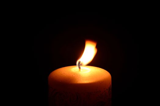 Photo of a white christmas candle burning on a black background. Objects photography.
