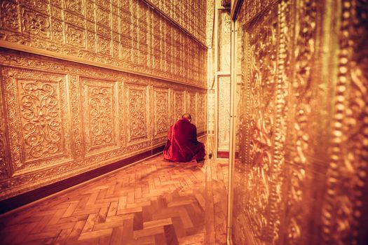 MYANMAR - FEBRUARY 9: Unidentified Monk in Red suit make meditation in big golden room at Botataung pagoda on February 09, 2014 in Yangon, Myanmar