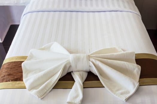 White Towel folded in bow shape on bed