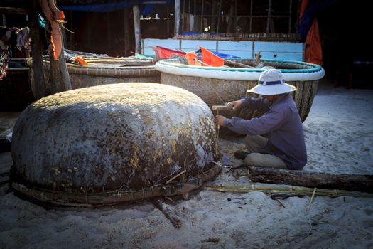 Phu Quoc, Vietnam - November 2nd, 2013: the man was repairing his coracle in the "Bai Kem" beach, Phu Quoc, Vietnam