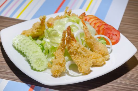 deep fried shrimp and  fresh vegetable salad on white dish