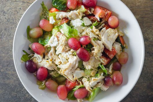 Mix salad with grapes and chicken on white dish