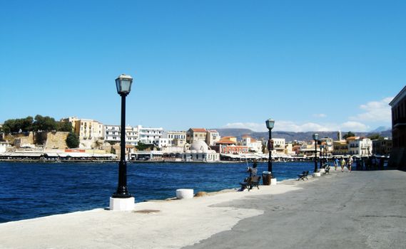 Man fishing and people walking at a distant view of the Old Port in Chania, Crete Island, Greece.

Picture taken on July 27, 2010.