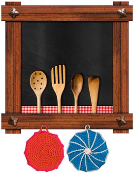 Empty blackboard with wooden frame and ancient nails, four wooden kitchen utensils, two wool pot holders, red and white checkered tablecloth isolated on white background
