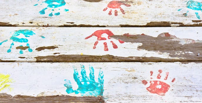 Hand prints in red and blue paint on a white wooden surface