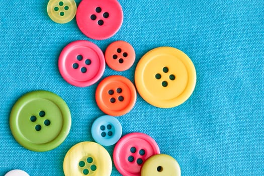 Colorful plastic buttons on blue textile, as a background image