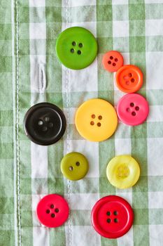 Colorful plastic buttons on a checked shirt as a background image
