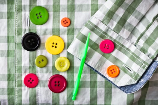 Colorful plastic buttons on a checked shirt as a background image
