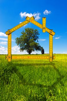 Wooden yellow meter tool forming a ecologic house in the countryside