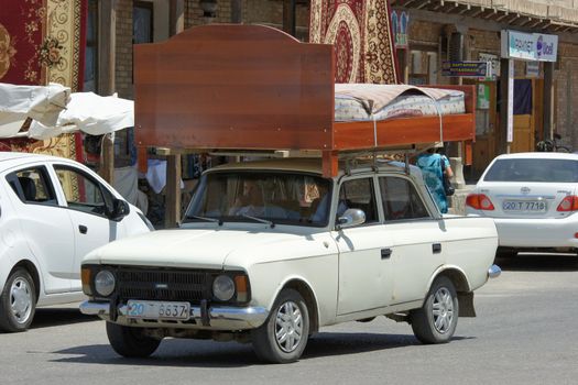 BUKHARA, UZBEKISTAN - MAY 23, 2012: People transporting furniture with an old car on May 23, 2012 in Bukhara, Uzbekistan, Asia