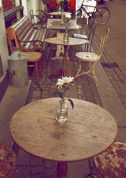 Empty Sidewalk Cafe with Wooden Tables and Old Chairs on Cobblestone Street in Copenhagen Outdoors