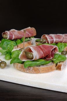 Toasted slices of jamon jerked pork leg with capers and basil