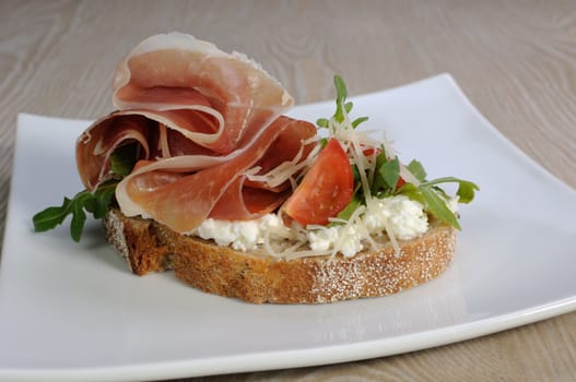 Sandwich of jamon with ricotta, arugula, cheese and a slice of cherry