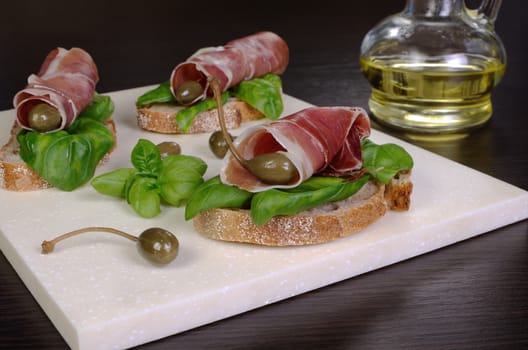 Slice Uncooked jerked pork ham jamon with capers and basil