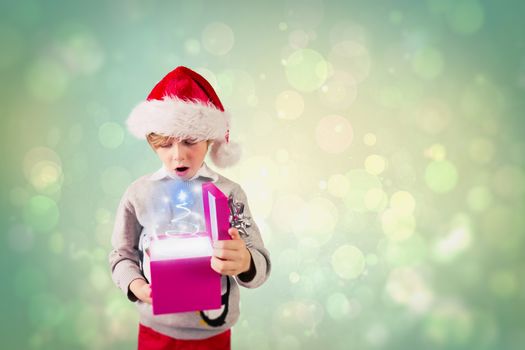 Festive boy holding a gift against green abstract light spot design