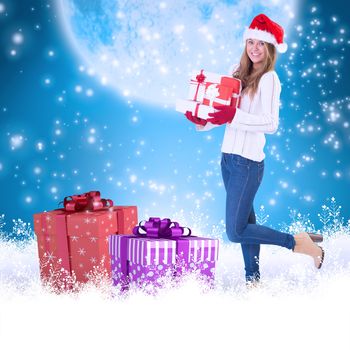 Festive blonde holding pile of gifts against blue background with vignette