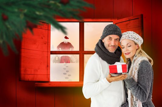 Happy winter couple with gift against festive fir branch with baubles 