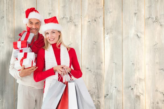 Happy festive couple with gifts and bags against pale wooden planks
